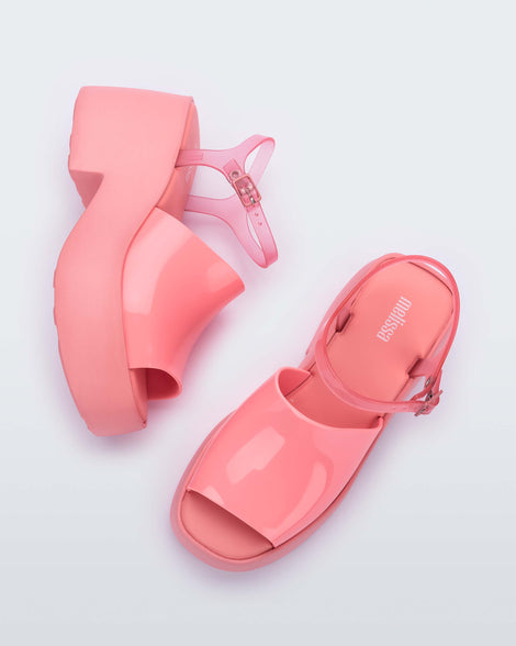 A top and side view of a pair of pink Melissa Pose platform sandals with a pink front strap, a clear pink ankle strap and a pink sole.