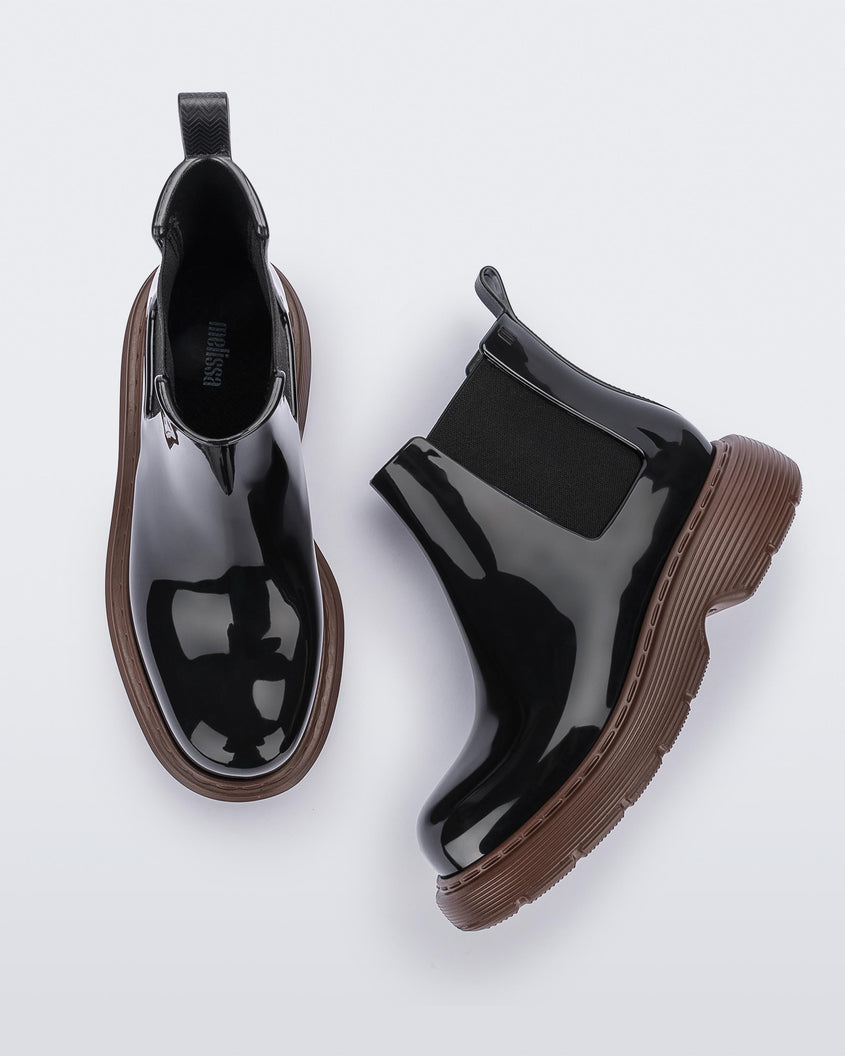 Top and side view of a pair of Melissa Step slip on ankle boots with bronze sole and black upper.
