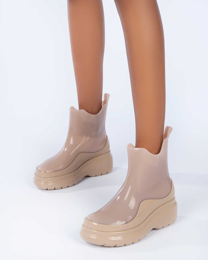 A model's legs wearing a pair of brown Melissa Grip short rain boots.