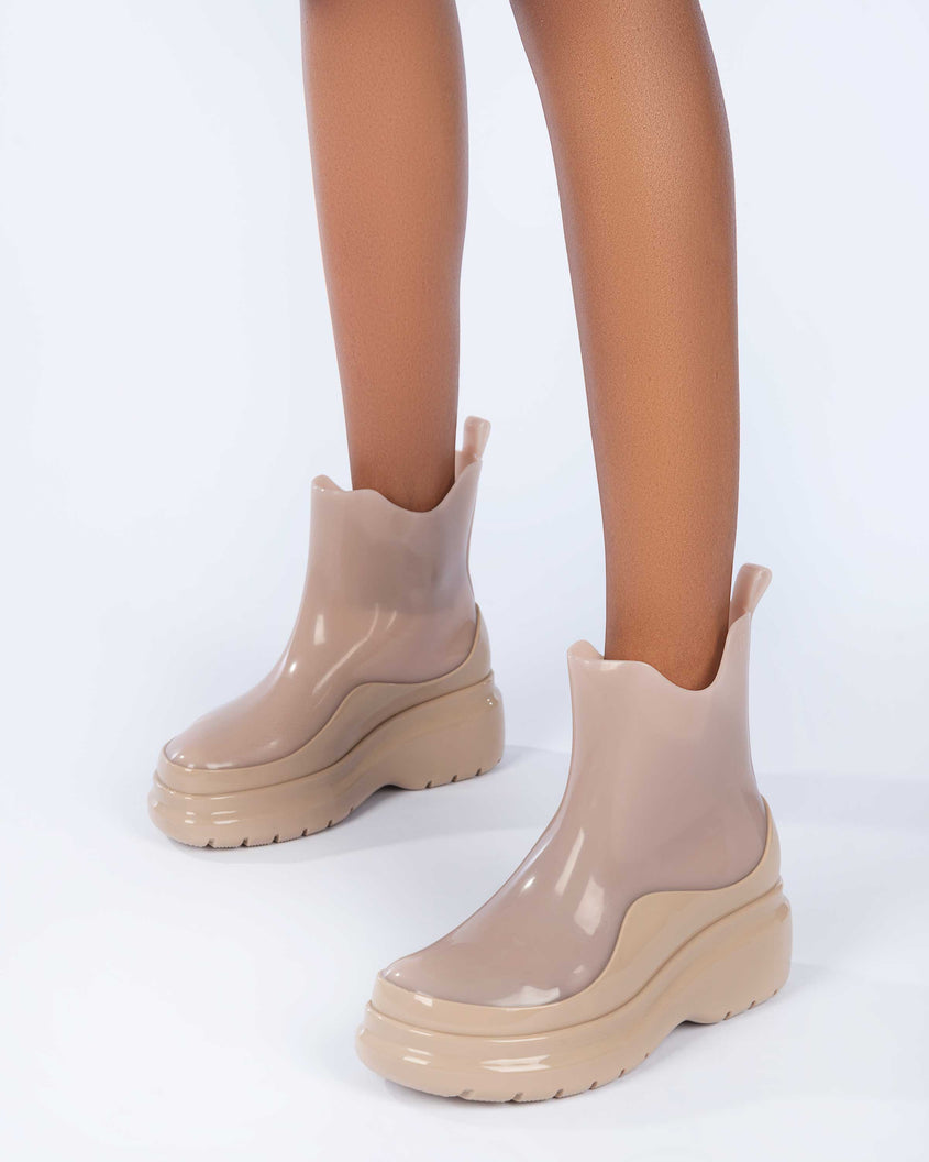 A model's legs wearing a pair of brown Melissa Grip short rain boots.