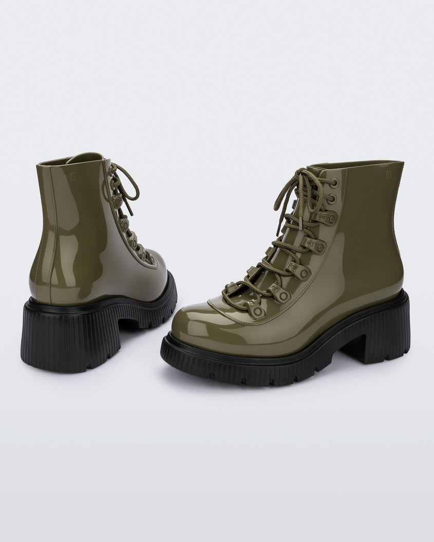 An angled back and side view of a pair of black/green Melissa Cosmo boots with a green base, laces and a black heel sole