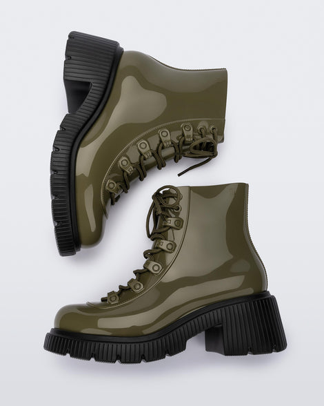 A side view of a pair of black/green Melissa Cosmo boots with a green base, laces and a black heel sole, laying on their side.