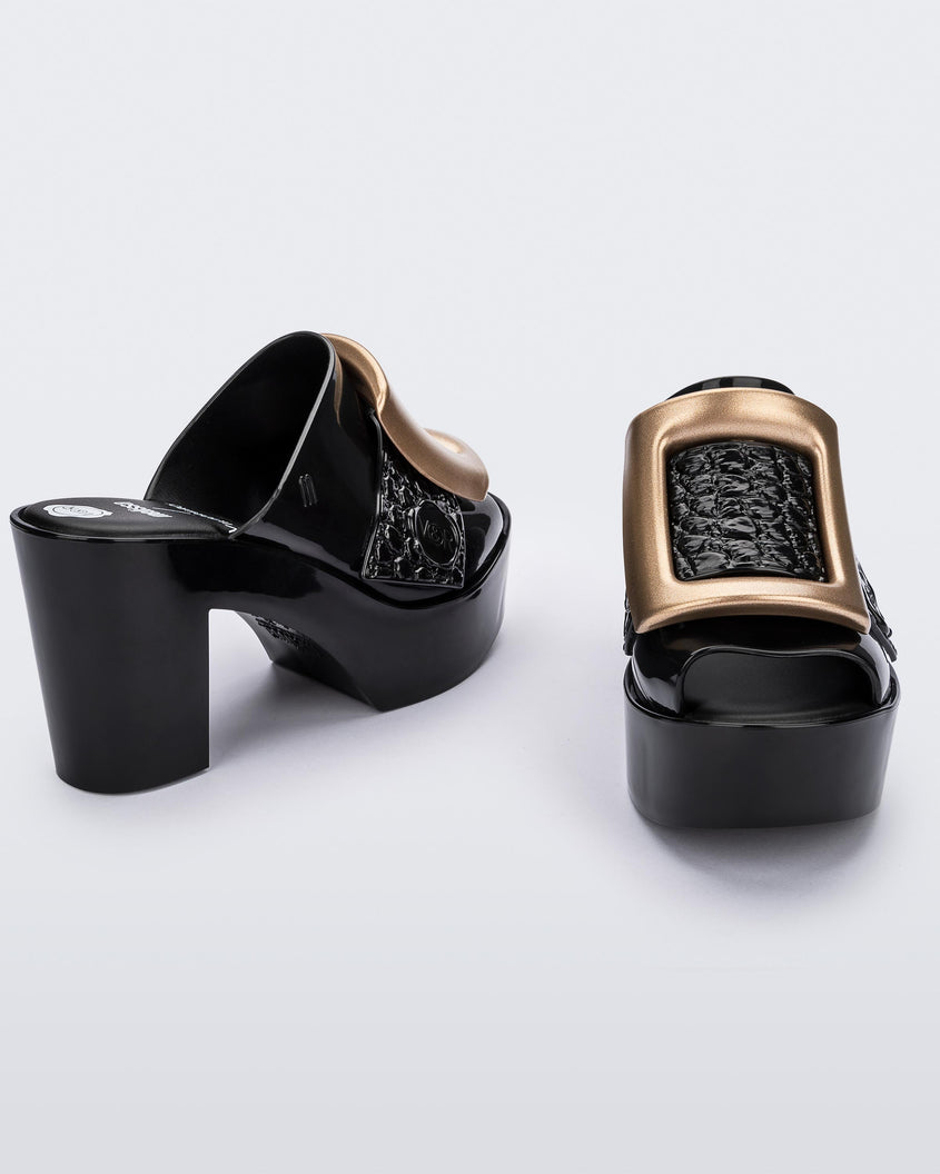 Angled view of a pair of black Melissa's Buckle Up heeld mules with a gold buckle.