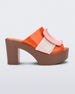 Side view of orange/brown Melissa Buckle Up heeled mule with ivory strap and pink buckle.