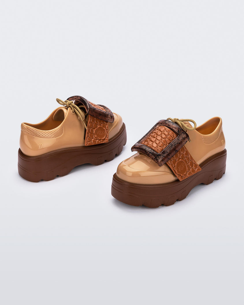 Angled view of a pair of brown/beige Melissa Buckle Up Kick Off platform sneakers.