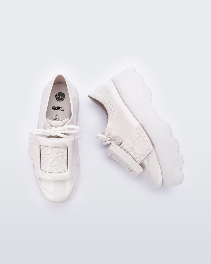 Top and side view of a pair of white Melissa Buckle Up Kick Off platform sneakers.