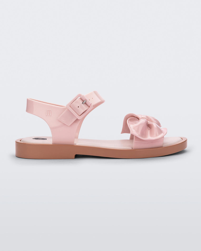 Side view of a Melissa Tie Mar sandal with beige sole, pink ankle straps with buckle closure and pink 3D bow detail on front straps 