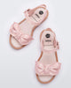 Top view of a pair of Melissa Tie Mar sandals with beige sole, pink ankle straps with buckle closure and pink 3D bow detail on front straps 