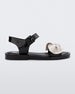 Side view of a Melissa Tie Mar sandal in black with buckle ankle strap and beige 3D bow detail on front straps