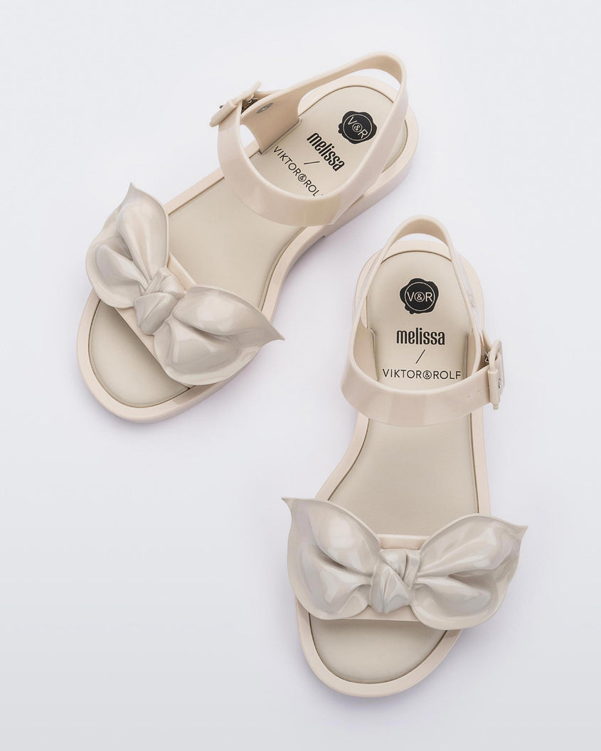 A top view of a pair of Beige/Beige Melissa Tie Mar Sandals with a beige base, an ankle strap and a front strap with a beige bow on the front.