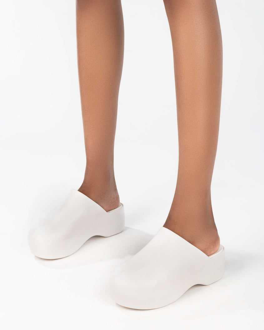 A model's legs wearing a pair of macadamia Melissa Bubble Matte mules.