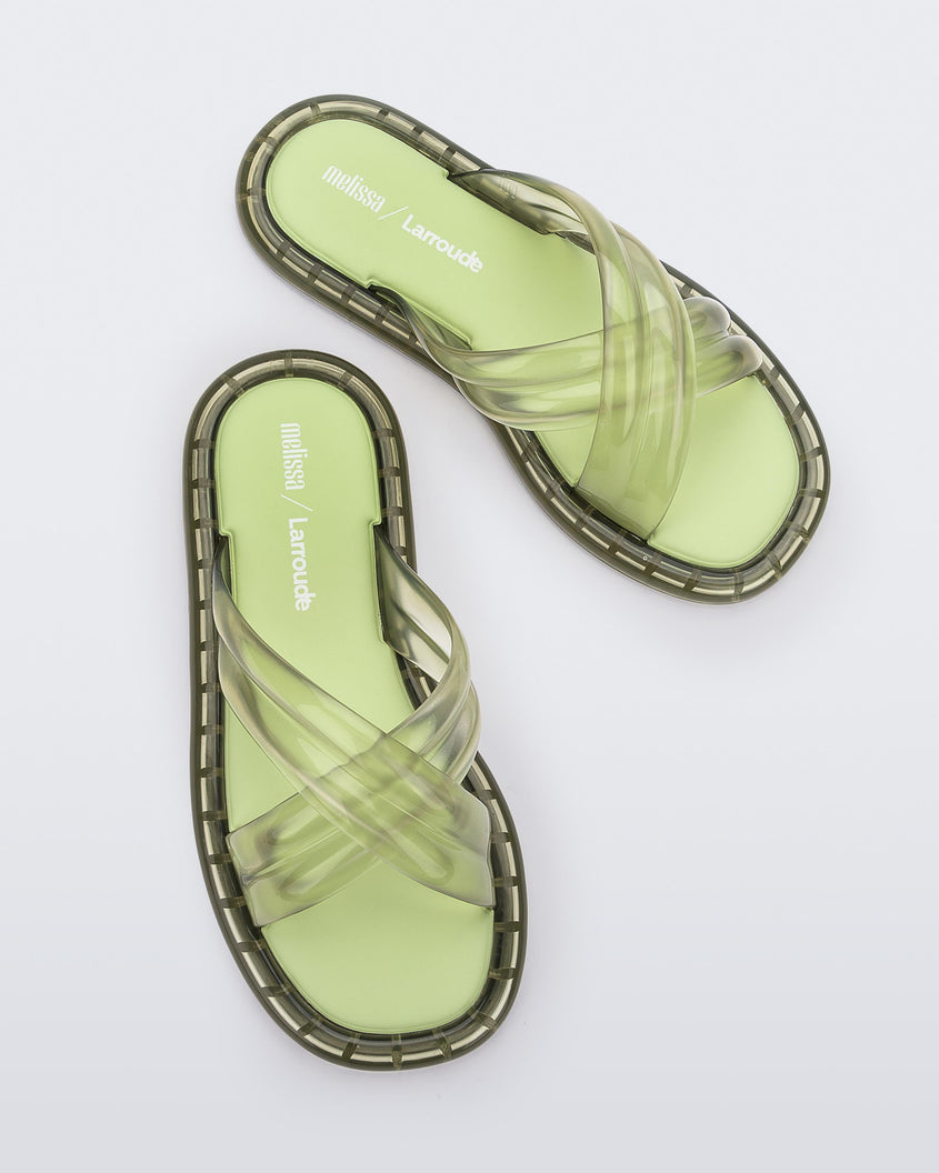 Top view of a pair of transparent green Melissa Cali slides with cross straps.