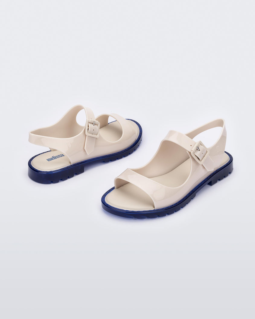 Angled view of a pair of white Melissa Bae sandals with blue soles.