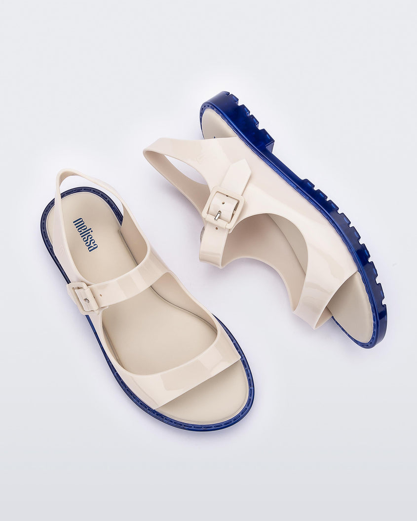 Top and side view of a pair of white Melissa Bae sandals with blue soles.