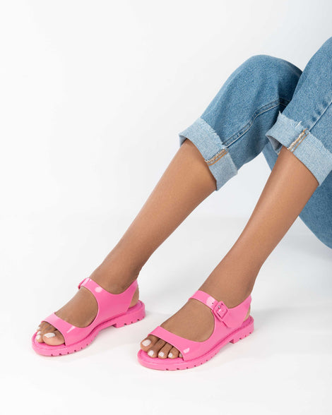 A model's legs wearing a pair of pink Melissa Bae sandals.