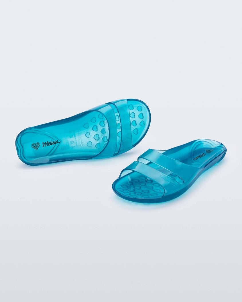 A front and top view of a pair of a clear blue Melissa Real Jelly Slides with two front straps.