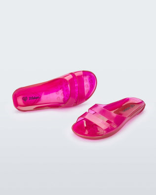 An angled front and side view of a pair of clear pink Melissa Real Jelly Slides with two front straps.