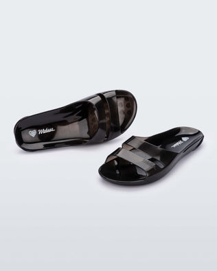 An angled front and top view of a pair of Transparent Black Melissa Real Jelly Slides with two front straps.