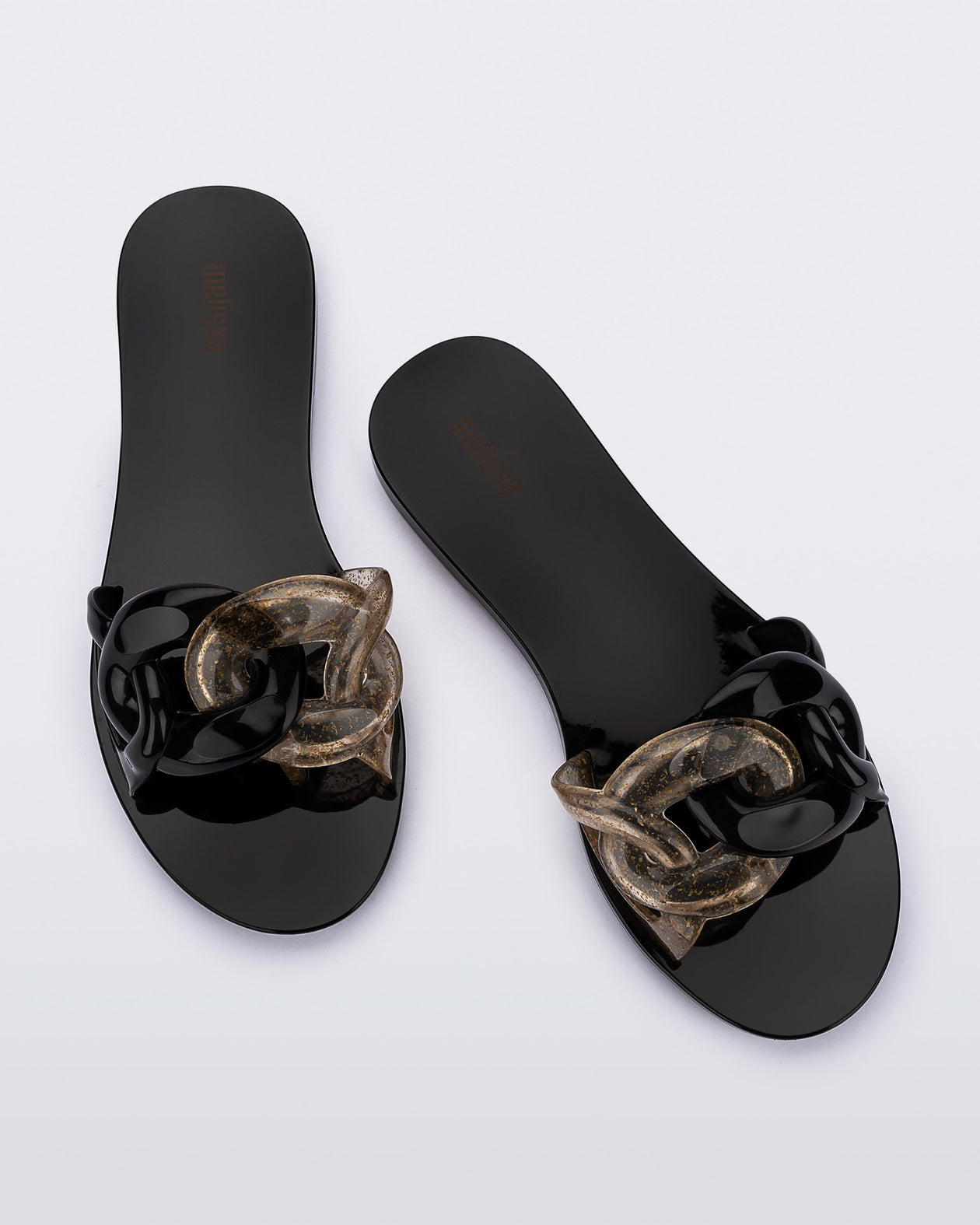 Top view of a pair of black Melissa Jelly Chain slides with a black and clear gold glitter chain detail.