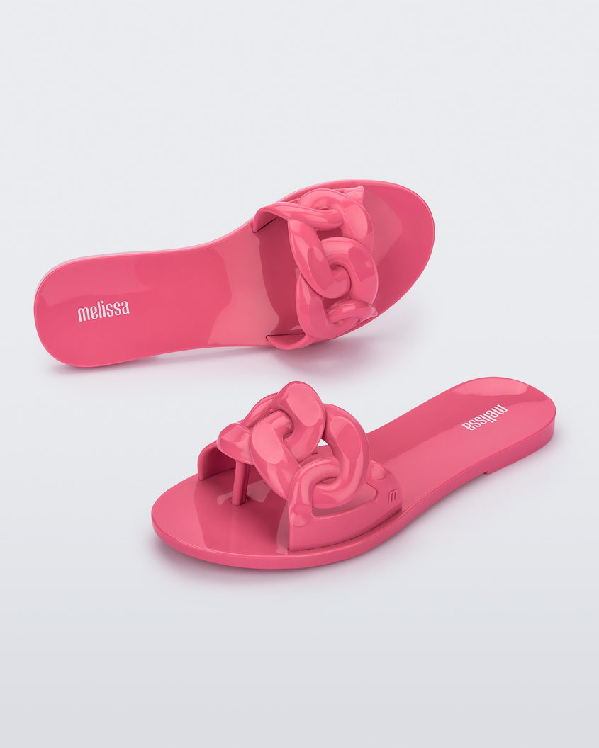An angled top and side view of a pair of pink Melissa Jelly Chain slides with a pink chain detail.