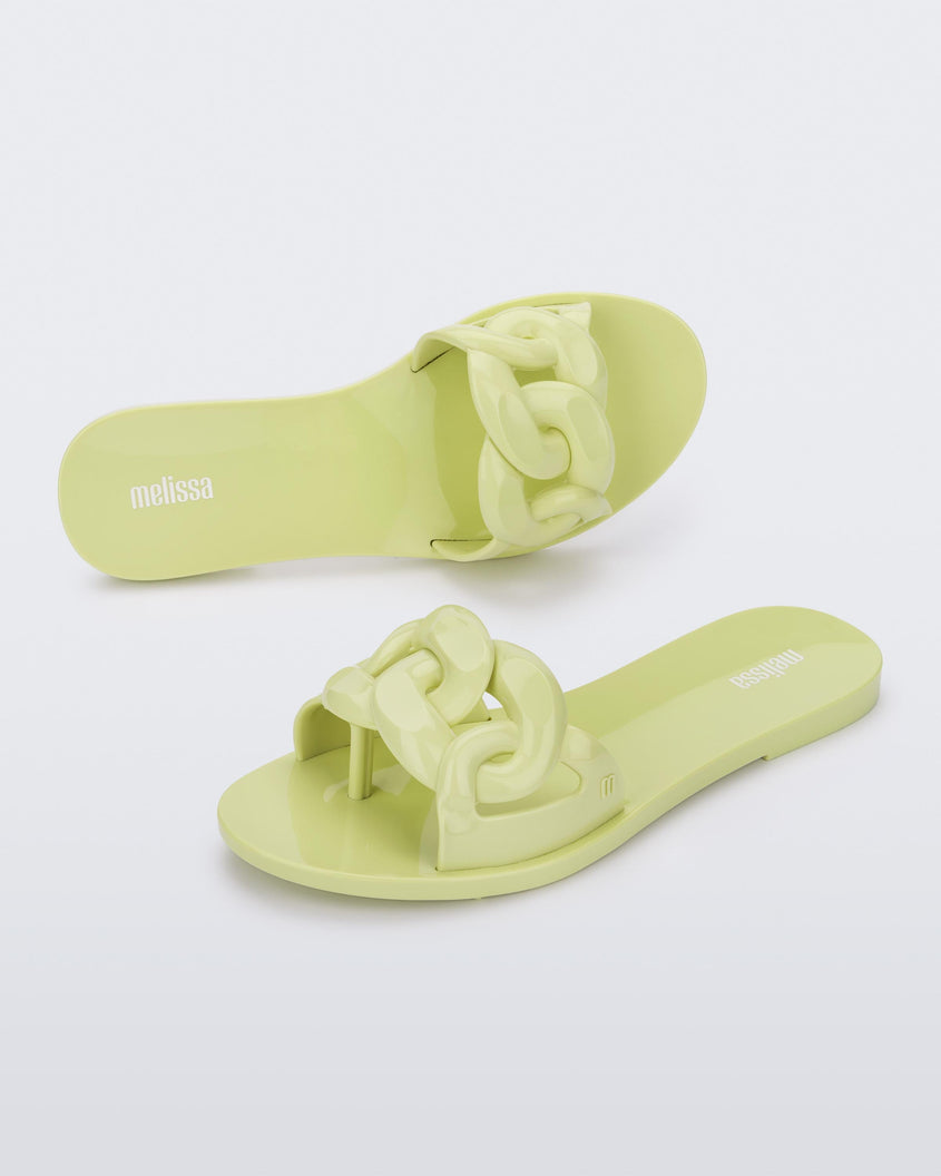 An angled top and side view of a pair of green Melissa Jelly Chain slides with a green chain detail.