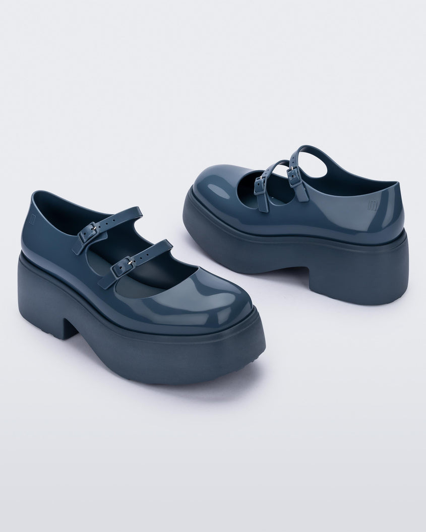 Side view of a pair of blue Melissa Farah platform shoes with two straps fastened by blue buckles.
