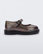 Side view of a clear multicolor glitter Mini Melissa Lola loafer with a rounded toe, strap and black buckle.