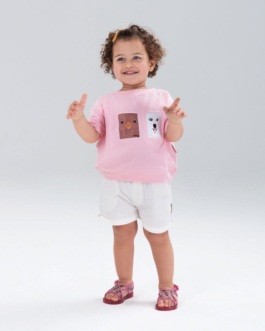 A little girl wearing Mini Melissa pink Acqua sandals with Minnie Mouse print.