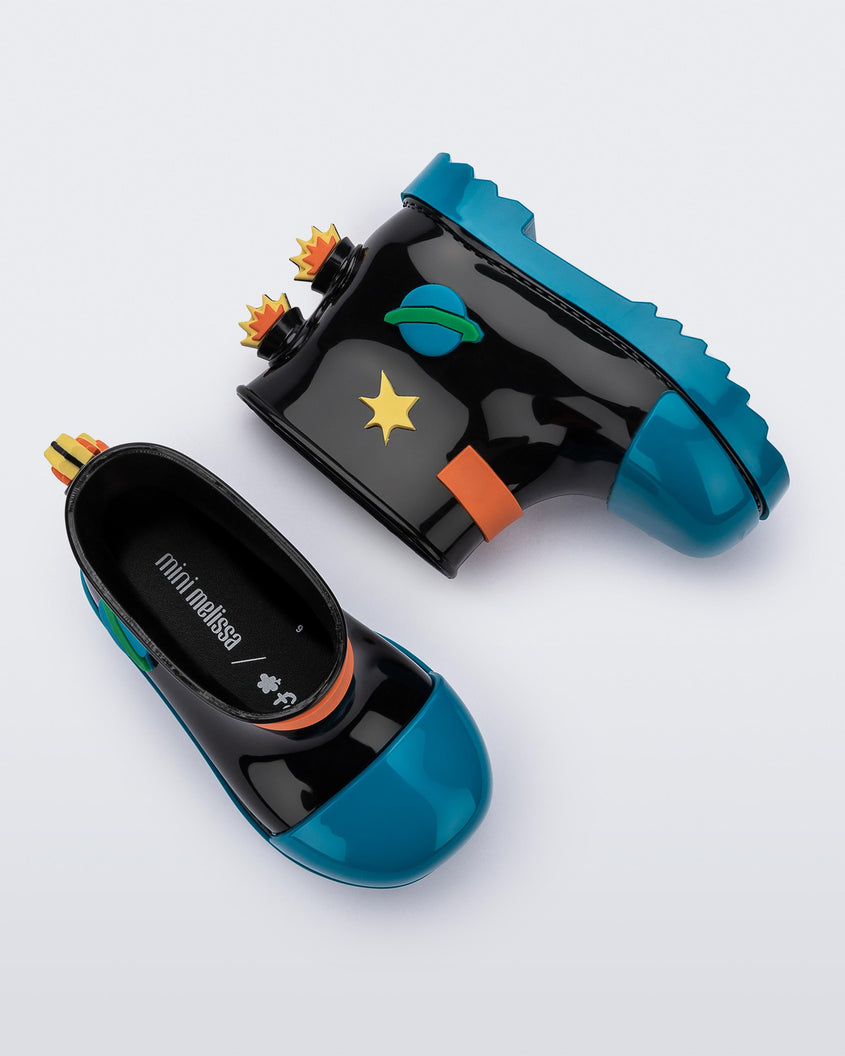A side and top view of a pair of blue/black Mini Melissa Rain Boots with a black base, blue toe, blue sole, and a planet, star and fire detail on the side and back.