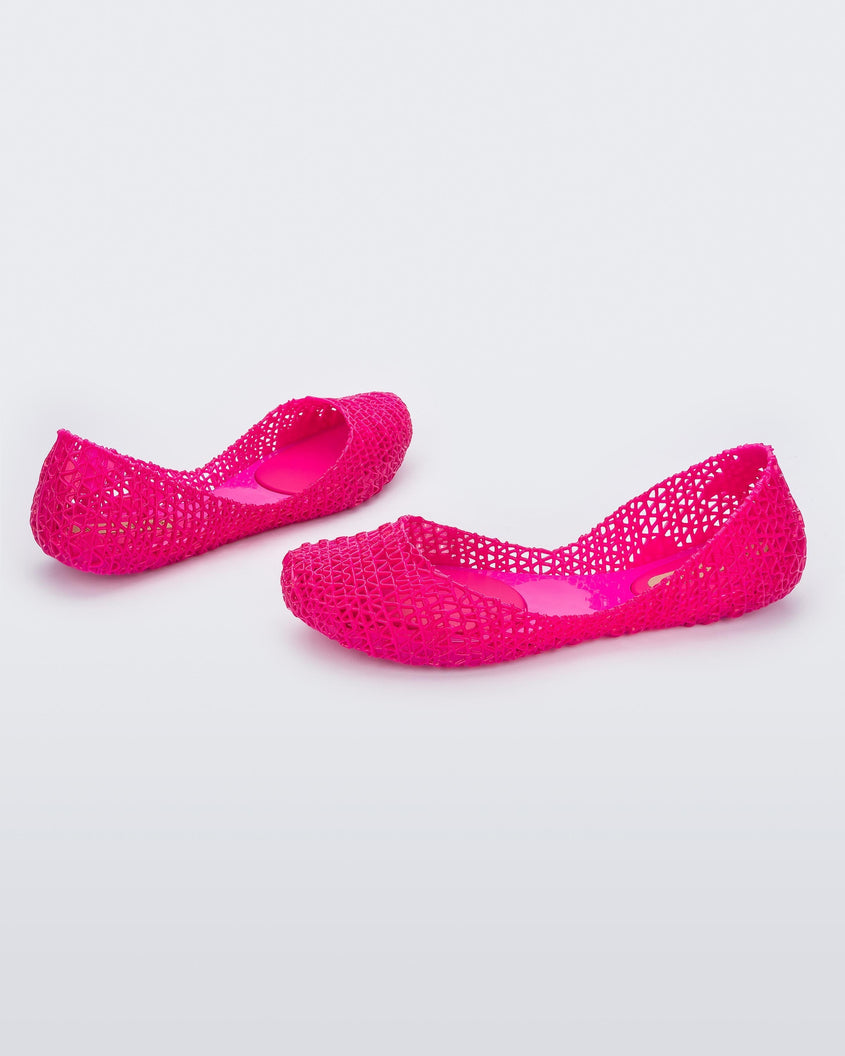 Angled view of a pair of Melissa Campana flats in bright pink with an open woven texture. 