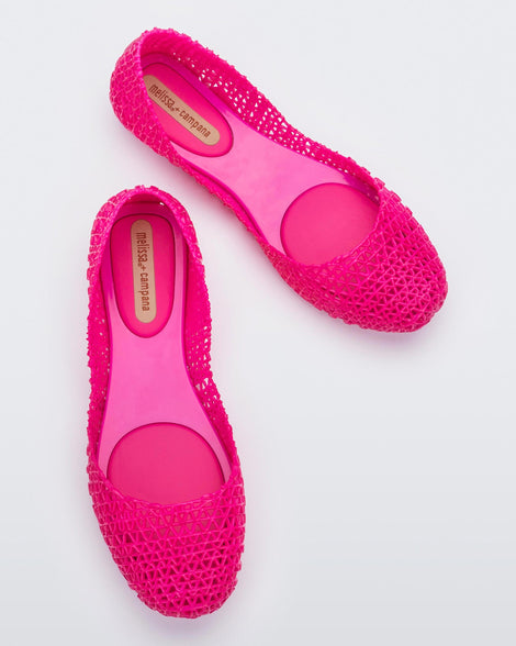 Top view of a pair of Melissa Campana flats in bright pink with an open woven texture.