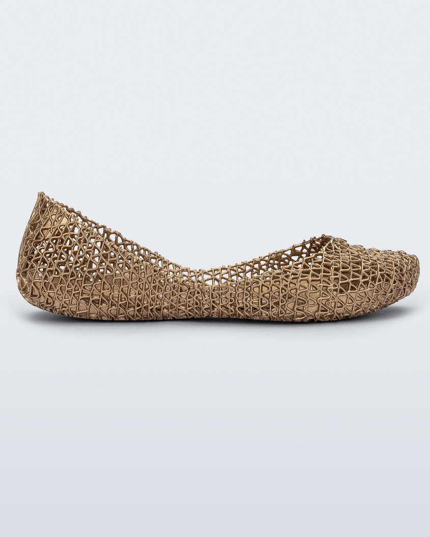 Side view of a gold Melissa Campana flat with an open woven texture.