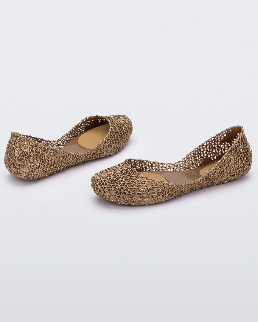 Angled view of a pair of Melissa Campana flats in gold with an open woven texture. 
