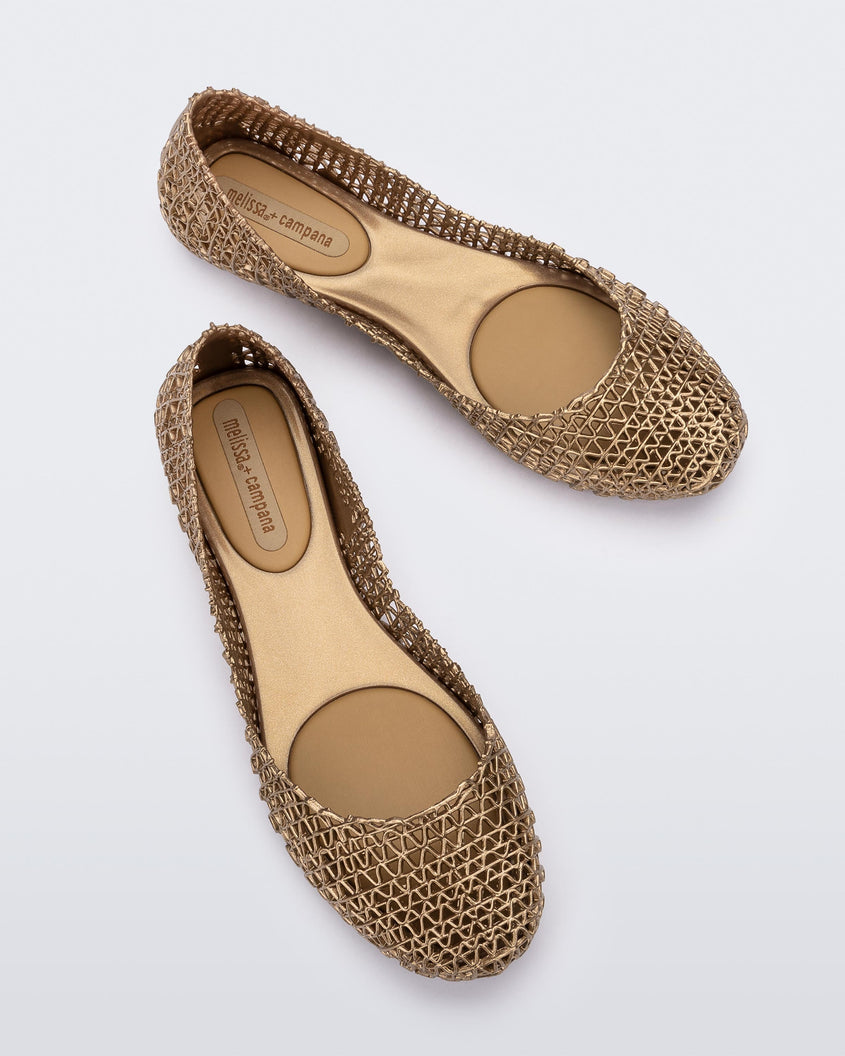 Top view of a pair of Melissa Campana flats in gold with an open woven texture.