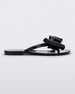 Side view of a black Melissa Harmonic Sweet flip flop with a black and glitter bow.