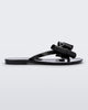 Side view of a black Melissa Harmonic Sweet flip flop with a black and glitter bow.