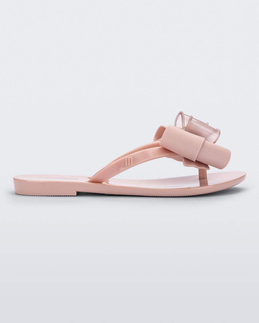 Side view of a light pink Mini Melissa Harmonic Sweet flip flop with a light pink and glitter bow.