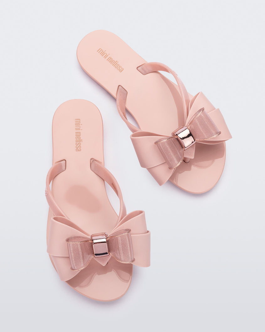 Top view of a pair of light pink Mini Melissa Harmonic Sweet flip flops with a light pink and glitter bow.