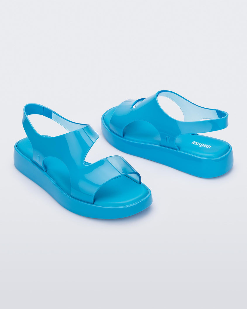 An angled side and front view of a pair of blue Melissa Franny sandals with straps.