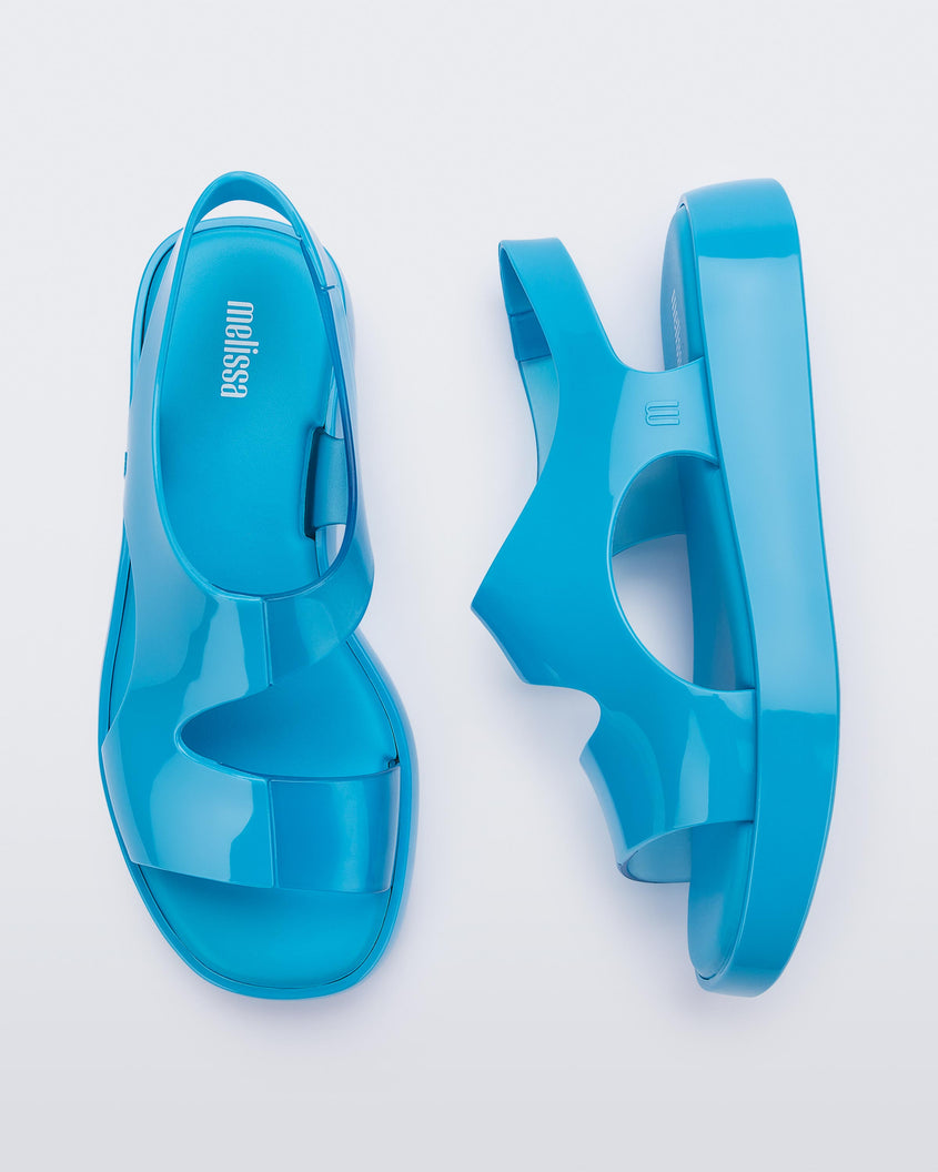 A top and side view of a pair of blue Melissa Franny sandals with straps.