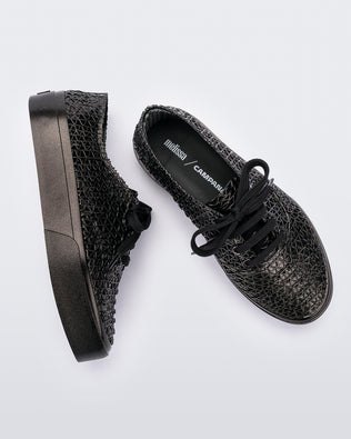 A top and side view of a pair of black Melissa Campana sneakers with a woven texture base and laces.