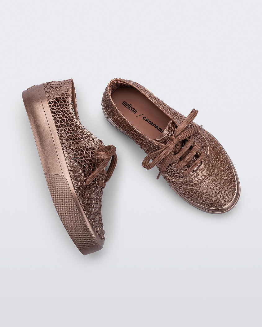 A top and side view of a pair of Melissa Campana Metallic Pink sneakers with a woven texture base and laces.