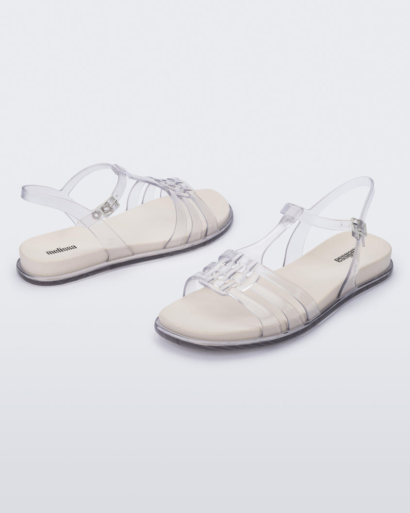 An angled side view of a pair of clear Melissa Party sandals with back ankle strap and buckle closure.