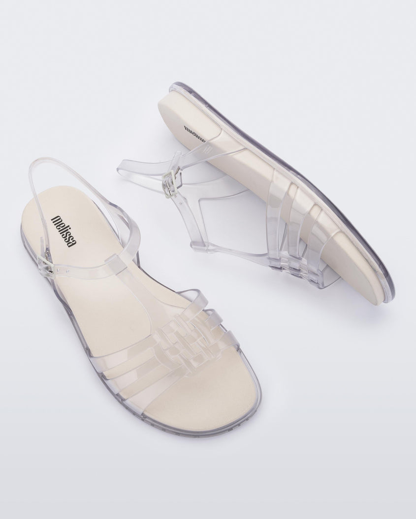 A top and side view of a pair of clear Melissa Party sandals with back ankle strap and buckle closure.