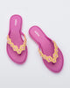 A top view of a pair of pink Melissa Spring Flip Flops with pink and yellow flowers on them.