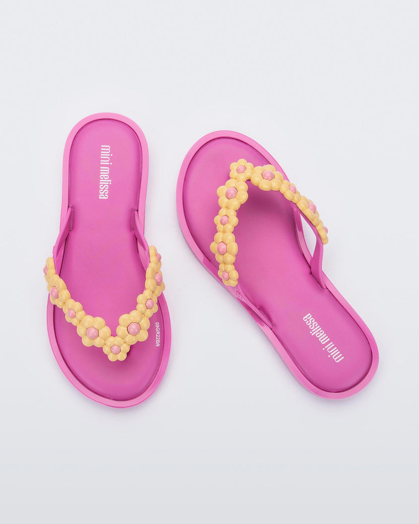 A top view of a pair of lilac Mini Melissa Spring Flip Flops with yellow and pink flowers.