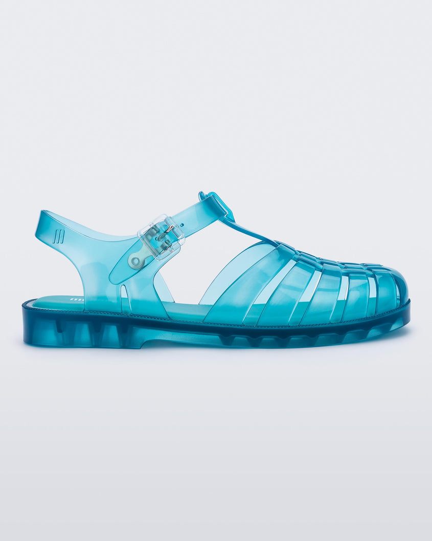 Side view of a transparent blue Melissa Possession sandal with a closed toe front weft design connected to a top strap with a buckle.