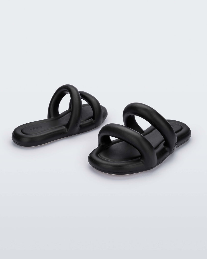 An angled back and front view of a pair of black Melissa Free Bloom Slides with puffer-like straps.