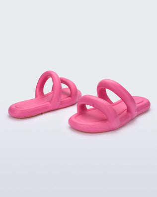 An angled side and front view of a pair of pink Melissa Free Bloom Slides with puffer-like straps.