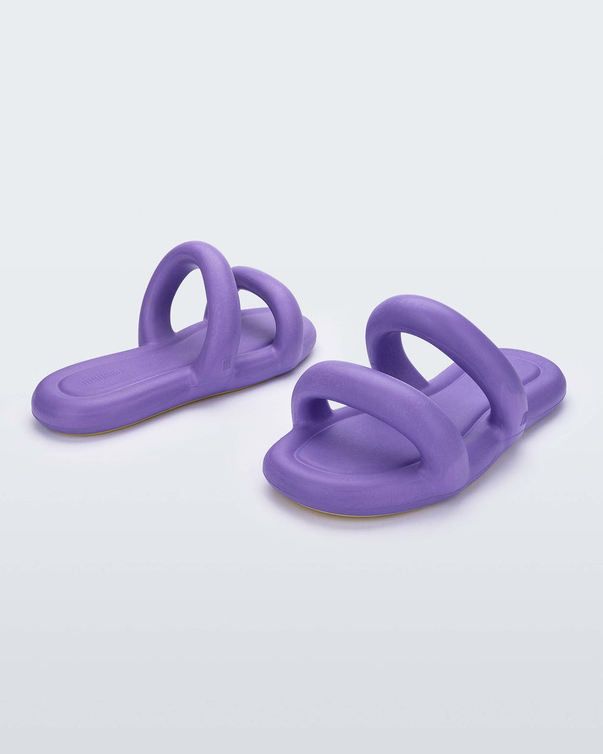 An angled back and front view of a pair of lilac Melissa Free Bloom Slides with puffer-like straps.